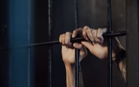 hands grasp prison bars