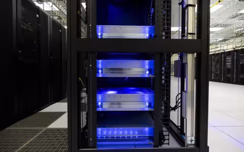 A photo of a black server cabinet with four silver racks illuminated blue from within.