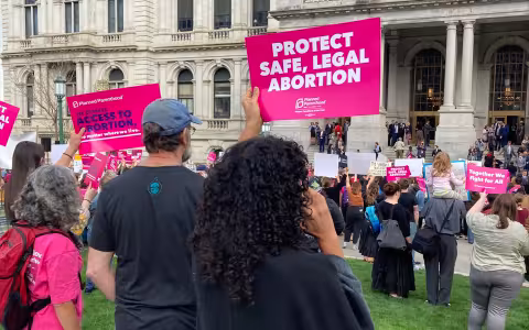 People holding up "protect Safe, Legal Abortion" and other signs at Abortion Rights rally outside the NYS Capitol building.