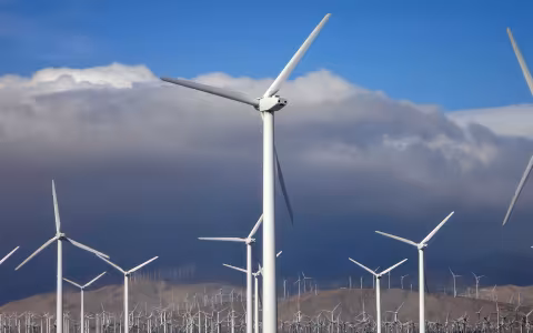 A field of wind turbines with dark clouds above them.
