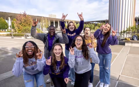 UAlbany students enthusiastically sharing their Great Dane hand signal on the podium