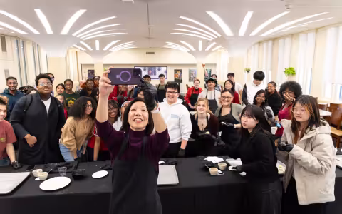Provost Carol Kim holds her cell phone up to get a selfie in front of a crowd of UAlbany students
