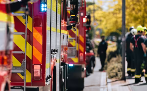 A group of first responders gather next to a line of fire engines to plan an emergency response.