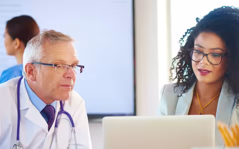 A clinical informatics specialist discusses an EHR-related issue with a doctor.