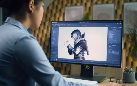 A video game designer works on a character model on a monitor.