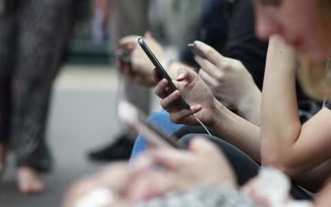 People seated next to each other scroll on their phones