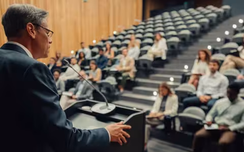 A communications professional leads a press conference in a lecture hall.