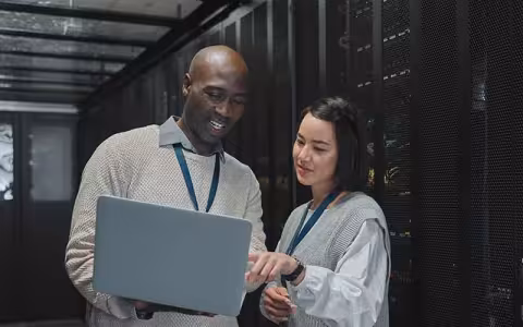 Cybersecurity professionals review data on a laptop in a data center.