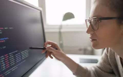 A cybersecurity professional analyzes code on a monitor.