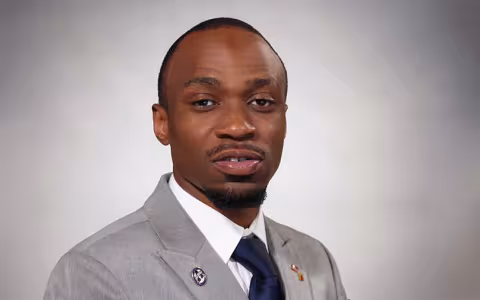 Christopher wearing a gray suit with a UAlbany pin.