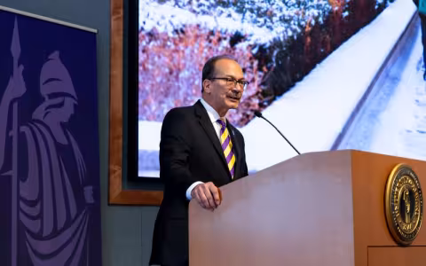 A man in a stiped tie speaks at a lecturn
