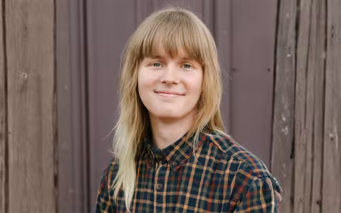 Portrait of a smiling Clark Mattoon standing in front of a wooden fence.