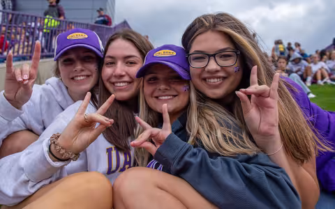 Four students making a Damien hand sign.