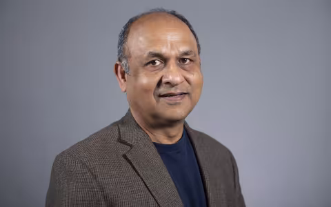 A portrait of UAlbany physicist Vivek Jain wearing a brown jacket and blue shirt.