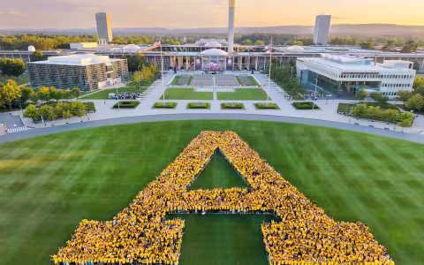 The UAlbany class of 2030 makes a letter "A" wearing yellow t-shirts on Collins Circle