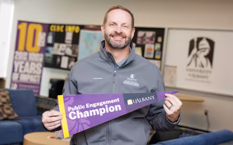 Mike Baumgardner holds up a Public Engagement Champion pennant.