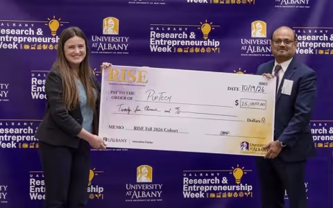 Two smiling people holding opposite ends of an oversized check for $25,000 made out to Puptech.