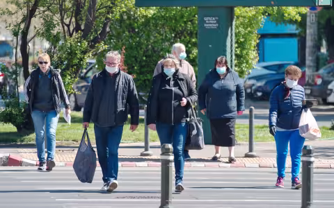 People in masks cross the street