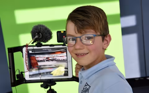 Boy standing in front of ipad smiling