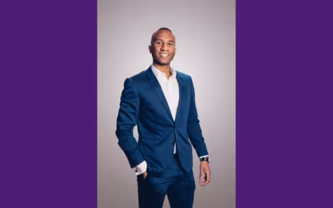 Man wearing a suit smiling at the camera.