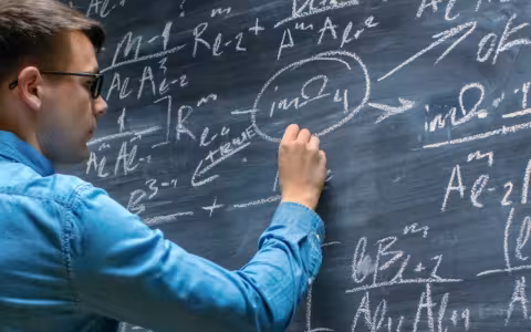 UAlbany student writing mathe problems on a chalk board