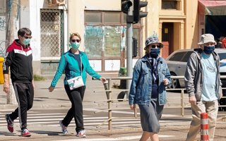 People in masks cross the street