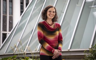 University at Albany sociologist Samatha Friedman stands by a glass stucture and smiles