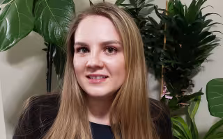 Portrait of Tatyana Tarasevich, wearing black. Plants can be seen in the background.