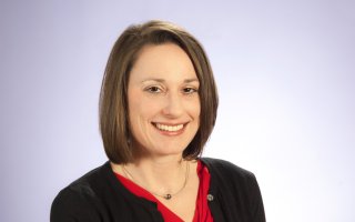 A portrait studio shot of professor Erika Martin, wearing a red shirt and black cardigan.