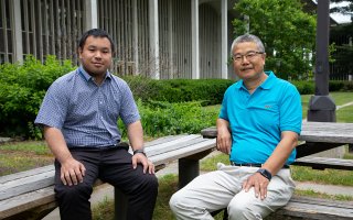 A young Chinese man and an elder Chinese man on benches in UAlbany courtyard