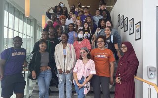 A group of about 40 student educators pose on a staircase.