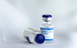 Two bottles of COVID-19 mRNA vaccines, one laying on its side.