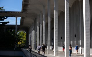 The School of Education is housed within Catskill, a building among those on the Academic Podium. Here, students are shown walking in front of Catskill on a clear, sunny day.