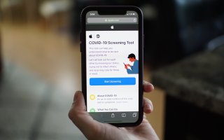 Person holds up phone with COVID-19 Screening Tool app opened.