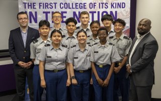 CEHC professors Unal Tatar and Benjamin Yankson stand with JROTC students in front of a CEHC banner.