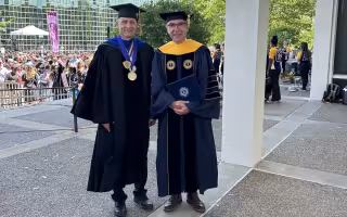 Igor Lednev and Jürgen Popp stand in academic regalia on the academic podium following UAlbany's 2023 undergraduate commencement ceremony.