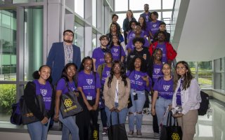  Students from the SPRINTER program, along with CEMHD Director Annis Golden and School of Public Health Professor Elizabeth Vasquez, pose for a group photo on a sunlit staircase in the RNA Institute.