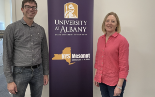 Nick Bassill and Jeannette Sutton stand in front of purple NYS Mesonet step and repeat banner.