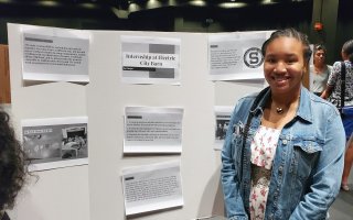 Schenectady's Ari Mayo stands in front of a poster she created describing her internship with Electrict City Barn.