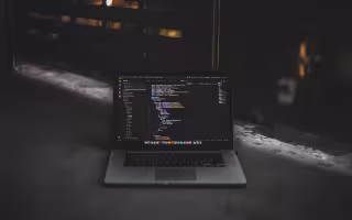 A laptop stands alone and displays lines of malicious code.