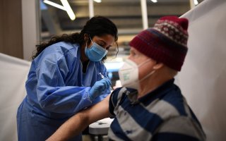 An older man is vaccinated by a nurse from the NYS National Guard at Yankee Stadium in the Bronx.