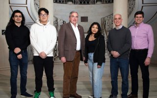A group of six people stand in a line inside Schenectady City Hall smiling, including Mayor Gary McCarthy.