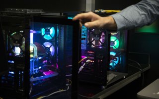 A hand reaches over the internal workings of computers