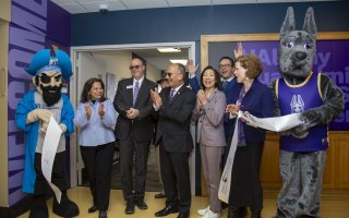 Life sized mascots of a pirate and a great dane flank a group of smiling and clapping people