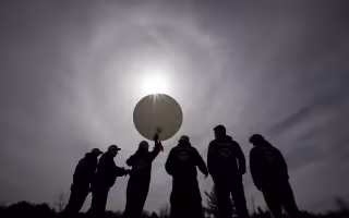 UAlbany students prepare to launch a weather balloon in near darkness at Fort Drum.