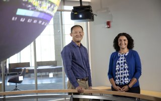 Brian Tang and Kristen Corbosiero stand next to the globe projector in the "Science on a Sphere" room at ETEC.