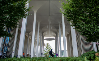 A person in a hoodie rides a bicycle across the podium on the UAlbany campus.
