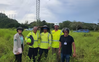 Researchers stand in front of a transmission tower in Puerto Rico.