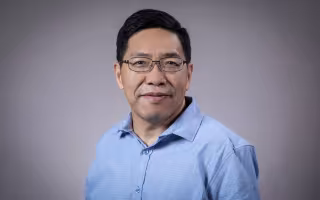 Headshot of Aiguo Dai wearing a blue button-down shirt.