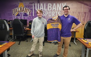 J.T. Stone and John Macone hold up a jersey inside the UAlbany Esports arena on the Downtown Campus.